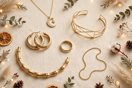 Celestial moon and star zirconia necklace, gold geometric bracelet, etched hoop earrings, gold ring, bamboo-textured gold choker and gold ball-chain necklace on a warm cream background